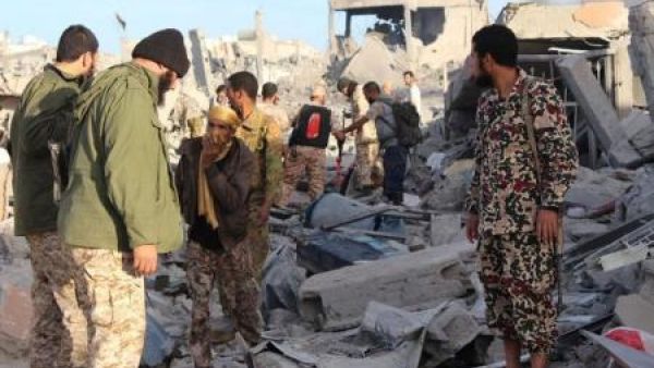 مقاتلون من القوات الليبية المتحالفة مع الحكومة المدعومة من الأمم المتحدة عند حطام منزل في سرت
