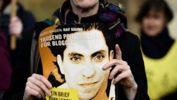 ناشطة من منظمة العفو الدولية تحمل صورة للمدون السعودي رائف بدوي خلال تظاهرة في برلين
