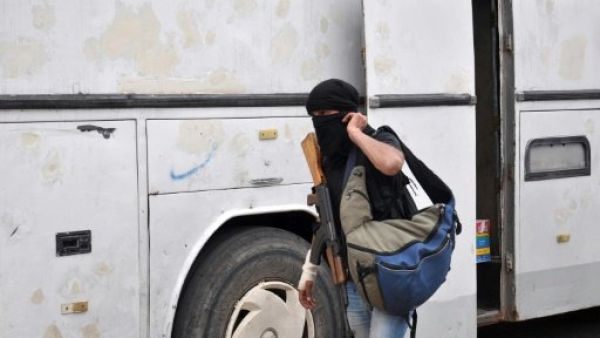 مسلح سوري معارض يستعد لركوب حافلة لمغادرة حي الوعر في حمص
