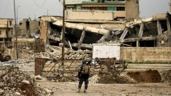 أحد أفراد قوات الشرطة الاتحادية العراقية يقف بالقرب من مبان مدمرة جراء اشتباكات مع مقاتلي تنظيم الدولة الإسلامية في الموصل


