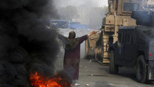 EGYPT, Cairo : An Egyptian woman tries to stop a military bulldozer from going forward during clashes that broke out as Egyptian security forces moved in to disperse supporters of Egypt's deposed president Mohamed Morsi in a huge protest camp near Rabaa al-Adawiya mosque in eastern Cairo on August 14, 2013. AFP PHOTO /MOHAMMED ABDEL MONEIM