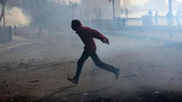 متظاهر يهرب من دخان القنابل المسيلة للدموع بالقرب من ميدان التحرير بالقاهرة/ا.ف.ب