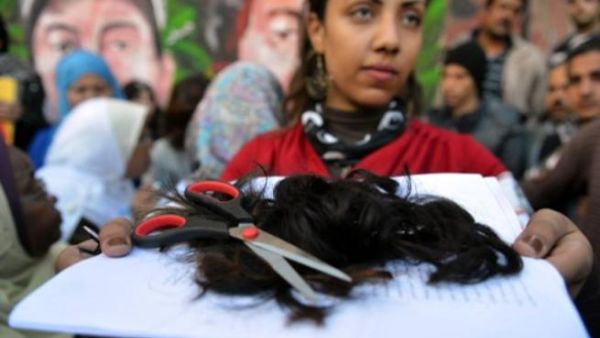 الناشطة المصرية فاطمة الشريف تقص خصلة من شعرها خلال تظاهرة احتجاج على الدستور/أ.ف.ب