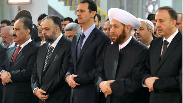 A handout picture released by the official Syrian Arab News Agency (SANA) on October 15, 2013 shows President Bashar al-Assad (C) and Syrian Grand Mufti Ahmed Hassun (C-R) praying at the Sayeda Hassiba mosque in the capital Damascus. (Image credit: AFP)