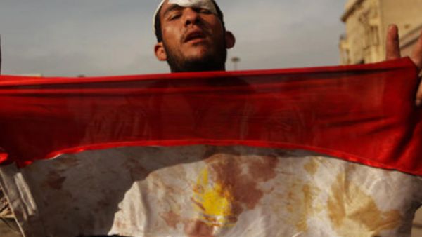 متظاهر يحمل علما ملطخا بالدماء