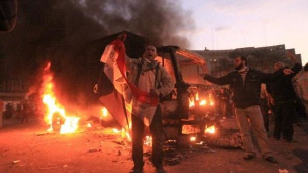 متظاهرون بجانب إحدى عربات الأمن المدمرة في ميدان التحرير 