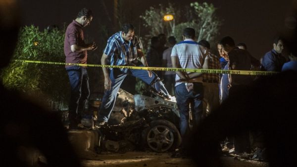 Egyptian officials inspect the wreckage of a car bomb that exploded in a Cairo suburb after Egypt's deputy prosecutor general drove by late on September 29, 2016, wounding a passerby. (AFP/Khaled Desouki)