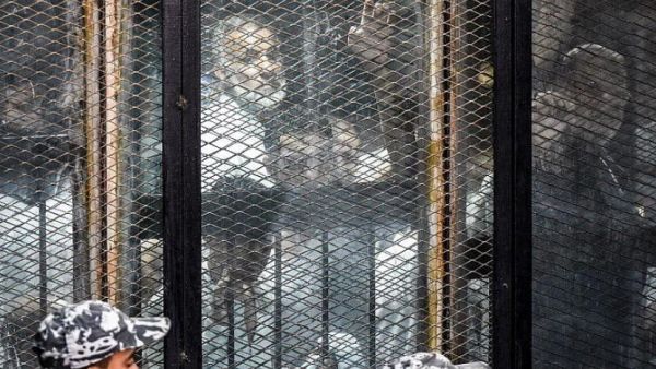 Essam el-Erian (R), one of the highest-ranking leaders of Egypt's banned Muslim Brotherhood, is seen alongside other members of the group inside a glass dock during their trial in the capital Cairo on July 28, 2018. (AFP Photo)