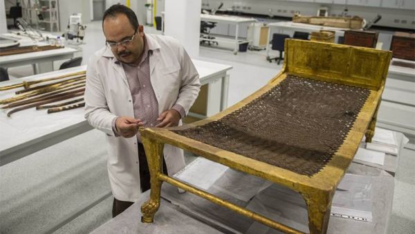 Egyptian archaeologist Medhat Abdallah cleans a gold-plated bed from Tutankhamen's treasures at the new Grand Egyptian Museum near the Giza pyramids in Cairo. (AFP)