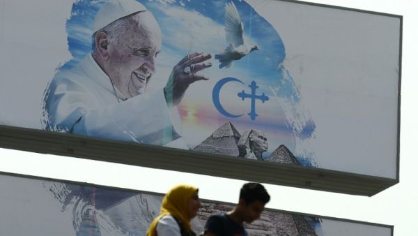 Egyptians walk past a welcome banner bearing a portrait of Pope Francis a day ahead of his visit to the capital Cairo, on April 27, 2017. (AFP/Mohamed El-Shahed)
