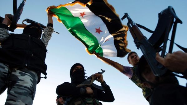 Free Syrian Army members raise their weapons and a revolutionary flag during a training session on the outskirts of Idlib, Syria. (AFP/File)