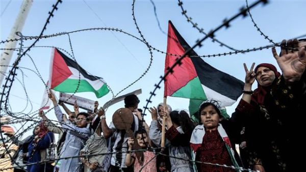 A girl raises a Palestinian flag as another Palestinian boy holds a wooden key symbolizing the return before the barbed-wire east of Gaza City on May 13, 2018. (AFP/ File Photo)
