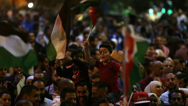 Children wave flags during a protest in Amman, Jordan, near the prime minister's office on June 4, 2018 / AFP