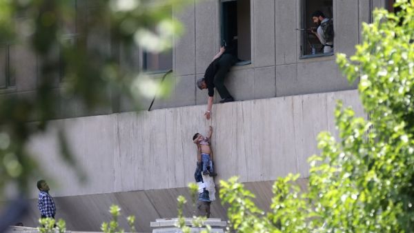 Iranian policemen evacuate a child from the parliament building in Tehran on June 7, 2017 during an attack on the complex. (Omid Vahabzadeh/Fars News/AFP)
