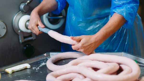 Butchers processing sausages at meat factory (Shutterstock/File Photo)