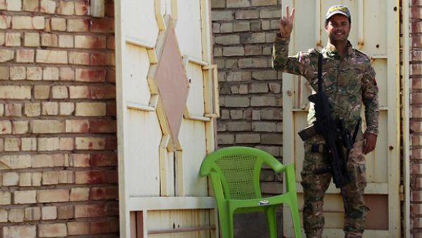 A member of Iraqi government forces flashes the sign of victory as he stands guard during an operation, backed by air support from the US-led coalition, in Fallujah's southern Shuhada neighbourhood to retake the area from the Islamic State (IS) group. (AFP/File)