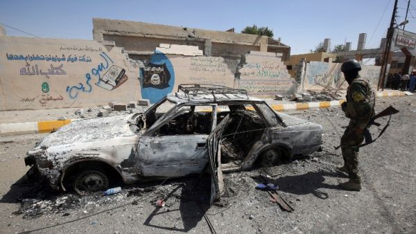 A member of the Iraqi government forces looks at a burnt-out vehicle as they secure the town of Sharqat, around 50 miles south of Mosul, on September 23, 2016, the day after recapturing city from Daesh. (AFP/Ahmad al-Rubaye)
