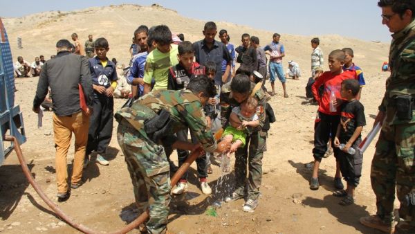 Peshmerga fighters wash the feet of a displaced Iraqi child from the northern village of Hawija as families rest under the protection of Peshmerga forces after fleeing from Daesh on August 17, 2016. (AFP/Marwan Ibrahim)