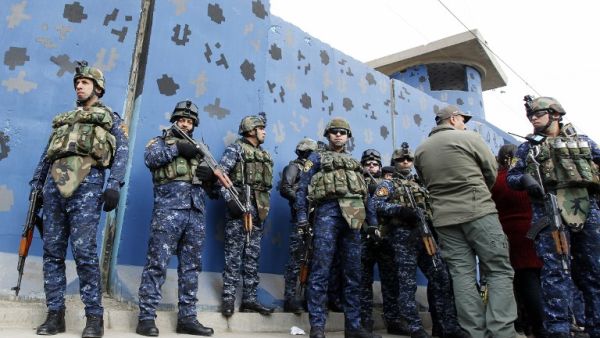 Iraqi policemen gather as they dismantle a security checkpoint on December 20, 2016 in Baghdad following a decision to reduce their number by more than 25 in east of the capital in order to ease traffic. (AFP/Sabah Arar)