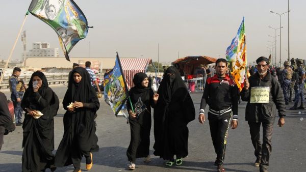 Iraqi security forces stand guard as Shia Muslim pilgrims walk on a road in Baghdad towards the holy city of Karbala a week ahead of the Arbaeen religious festival, the 40th day after Ashura, commemorating the death of Imam Hussein. (AFP/Sabah Arar)