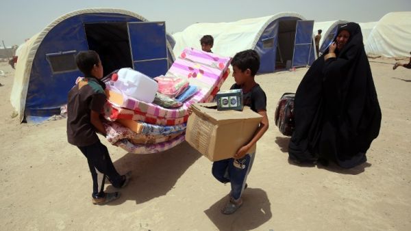 Iraqis displaced from the city of Fallujah collect aid distributed by the Norwegian Refugee Council at a newly opened camp in Amriyat al-Fallujah on June 27, 2016, south of Fallujah. (AFP/Ahmad al-Rubaye)