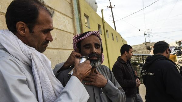 An Iraqi man gets his beard trimmed as civilians take a shelter inside a mosque in the village of Gogjali, as clashes go on between Iraq army forces and Daesh to retake Mosul, on November 2, 2016. (AFP/Bulent Kilic)