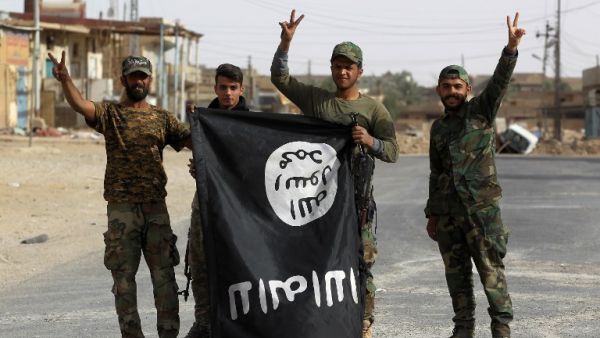 Iraqi members of the Hashed al-Shaabi (Popular Mobilisation Units) carry an upsidedown ISIS flag after victory in the city of al-Qaim (Ahmad Al-Rubaye/AFP)
