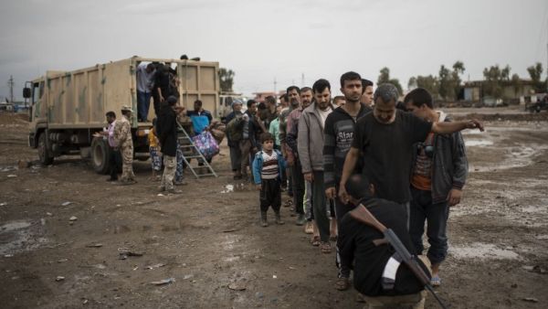 Displaced Iraqi men arrive at a processing center in western Mosul on April 14, 2017, before they are transported to refugee camps. (AFP/Christophe Simon)