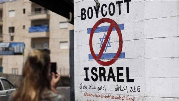A tourist photographs a sign painted on a wall in the occupied West Bank town of Bethlehem on June 5, 2015, calling to boycott Israeli products. (AFP)