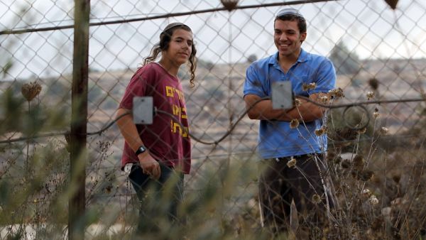 Two Israeli settlers watch Palestinian villagers following a price-tag attack in the West Bank. (AFP/File) Two Israeli settlers watch Palestinian villagers following a price-tag attack in the West Bank. (AFP/File)