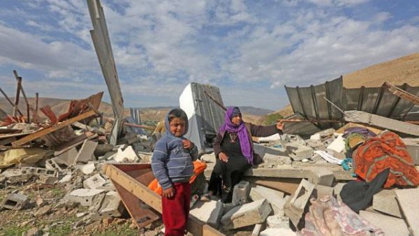 A Palestinian woman and her child check the rubble of their house after it was demolished by Israeli authorities. (AFP/File)