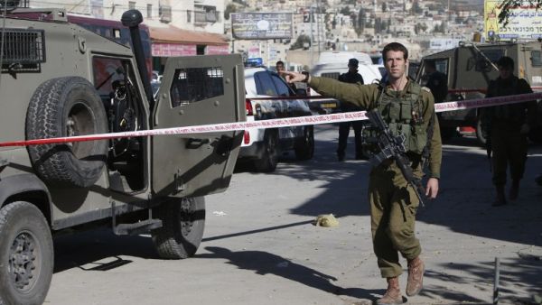 Israeli security forces check the site where a Palestinian man stabbed an Israeli soldier with a screwdriver before being shot and wounded, near the entrance to Hawara, south of the city of Nablus, on November 9, 2016. (AFP/Jaafar Ashtiyeh)