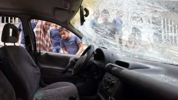 Palestinians look at a damaged car belonging to a Palestinian man who was killed by Israeli security forces after he attempted to ram his vehicle into Israeli border guards early in the morning in the Shufat refugee camp, in east Jerusalem, on September 5, 2016. (AFP/Hazem Bader)