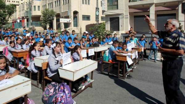 A Palestinian teacher gives a class during a protest by children and teachers against the reduction of educational programs in the West Bank. (AFP/File)
