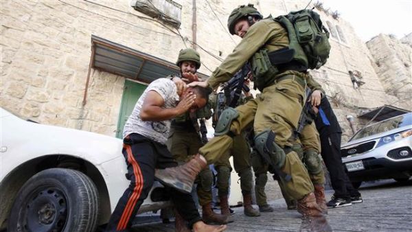 An Israeli soldier kicks a Palestinian man as troops try to arrest him in the southern West Bank city of Hebron. (AFP/ File)