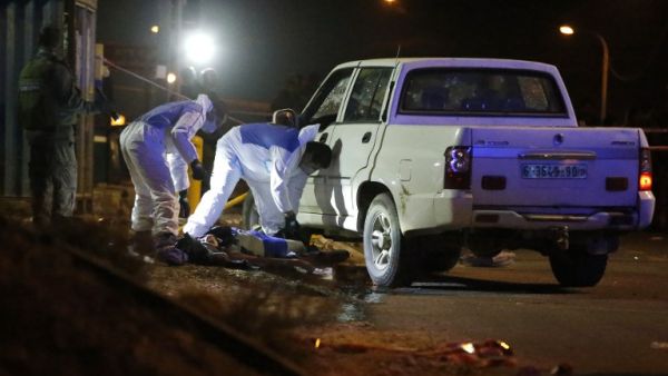 Israeli forensic policemen inspect the body of a Palestinian man who drove at a bus stop in an attempted car-ramming attack before being shot dead, east of Ramallah, on January 25, 2017. (AFP/Ahmad Gharabli)