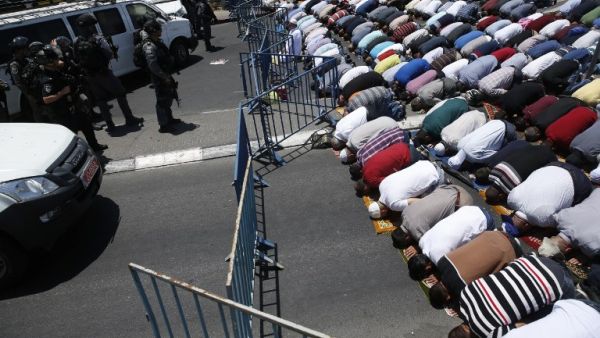 Muslim worshippers pray perform the traditional Friday prayers on a street outside the Lion Gate as Israeli police blocks the access to Al-Aqsa Mosque on July 14, 2017 (Ahmad Gharabli/AFP)