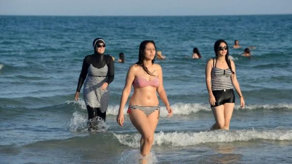A burkini-wearing woman (left) walks on a beach in Tunis. (AFP/Fethi Belaid)