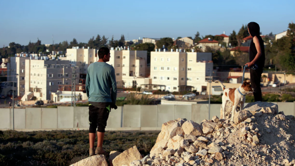 Palestinians in the Jalazone refugee camp in the West Bank look out at a wall surrounding an Israeli settlement. (AFP/File)