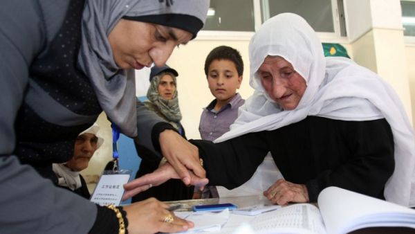 An elderly Jordanian woman is assisted by a member of the electoral commission as she votes in the parliamentary elections at a polling station in the capital Amman on September 20, 2016. (AFP/Khalil Mazraawi)