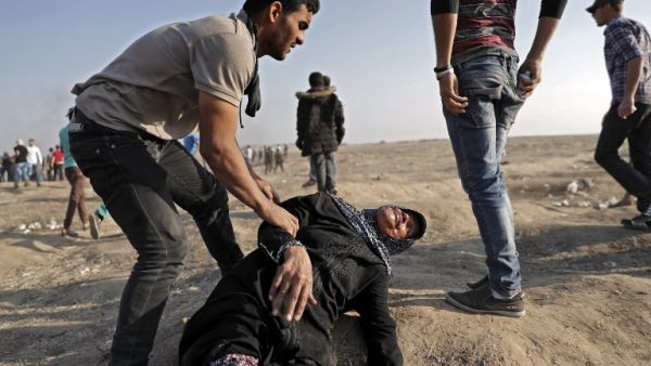 A Palestinian youth tends to a fallen old lady affected by tear gas during clashes with Israeli forces east of Gaza City /AFP