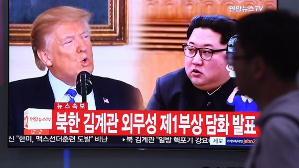 A man walks past a television news screen showing North Korean leader Kim Jong Un and US President Donald Trump/AFP