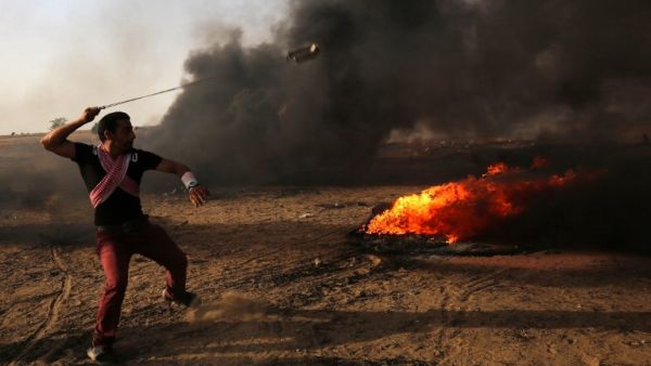 A Palestinian demonstrator uses a slingshot during clashes with Israeli forces along the border with the Gaza strip (AFP/File Photo)