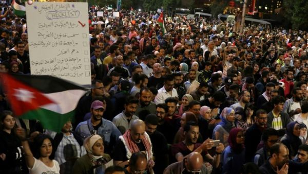 Demonstrators wave flags and hold signs during a protest in Amman, Jordan, near the prime minister's office, June 4, 2018. Protestors have demonstrated for the fifth night against the new proposed income tax draft law and other anti-austerity measures. Khalil Mazeraawi/ AFP) 
