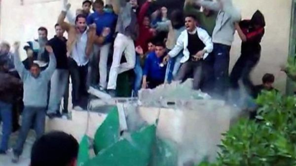 متظاهرون ليبيون يسقطون صورة كبيرة للعقيد القذافي في بنغازي