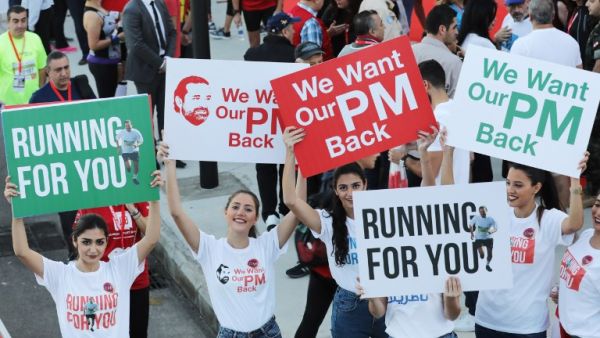 Supporters of Lebanon's resigned prime minister Saad Hariri hold up placards demanding his return from Saudi Arabia on the starting line of Beirut's annual marathon on November 12, 2017 (Anwar Amro/AFP)
