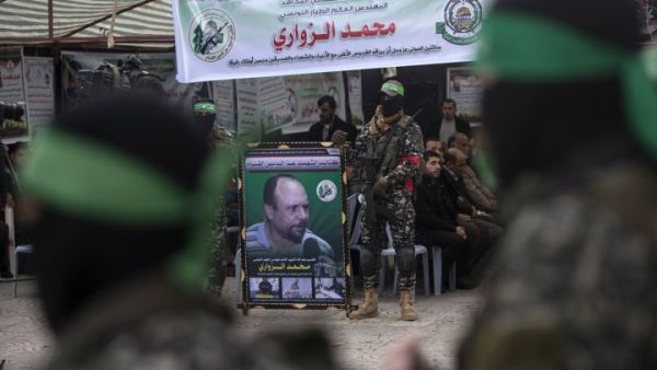 Members of Hamas' military wing hold a banner bearing a portrait of Mohamed Zaouari, who was murdered in Tunisia (AFP/File Photo)