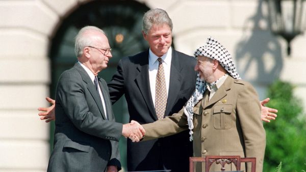 US President Bill Clinton stands between PLO leader Yasser Arafat and Israeli Prime Minister Yitzhak Rabin as they shake hands for the first time, on Sept. 13, 1993 (AFP)