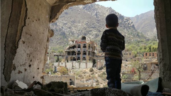 A photo of March 18, 2018, for a Yemeni child looking out at buildings damaged in an air strike in the southern Yemeni city of Taez. (AFP)