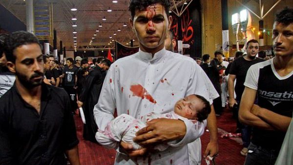 Young participant: A man holds a baby during an Ashura cutting ceremony, which sees male Shiite Muslims self-flagellate to commemorate the death of Imam Hussein, the grandson of the Prophet Muhammad, on the battlefield (AFP)